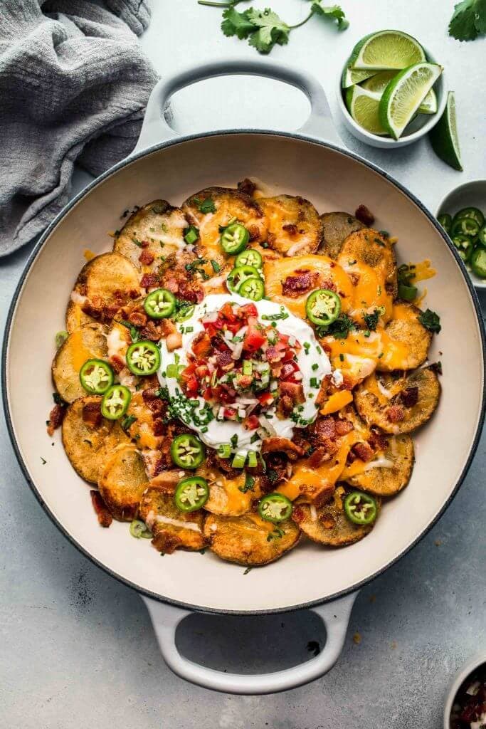 Overhead closeup of potato nachos topped with sour cream and pico de gallo.