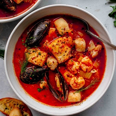 Overhead shot of cioppino in white bowl with spoon.