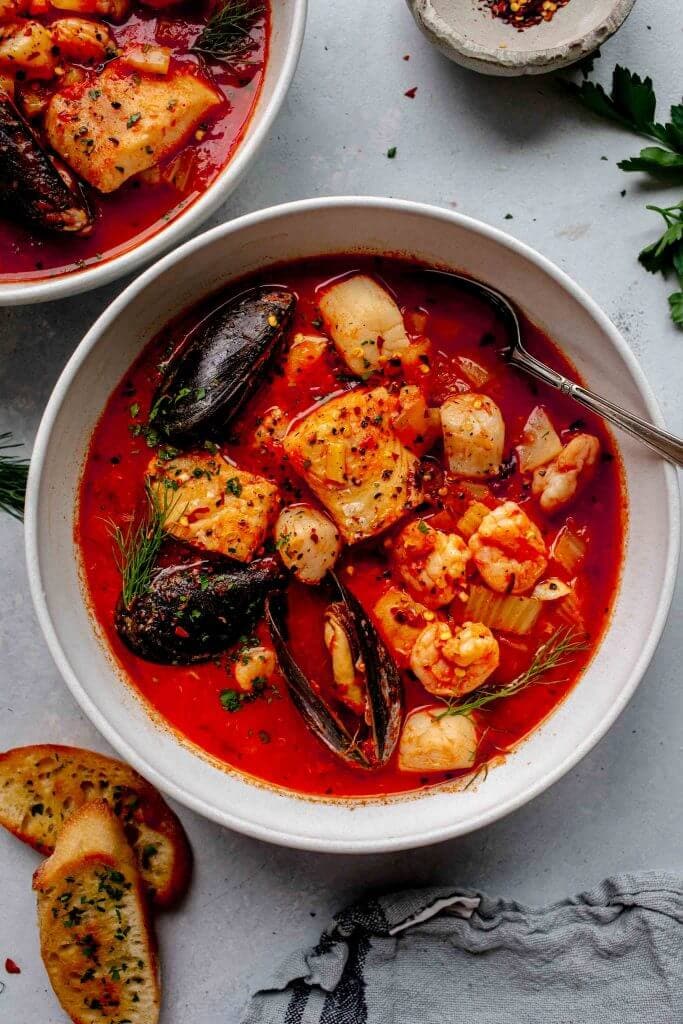 Overhead shot of cioppino in white bowl with spoon.