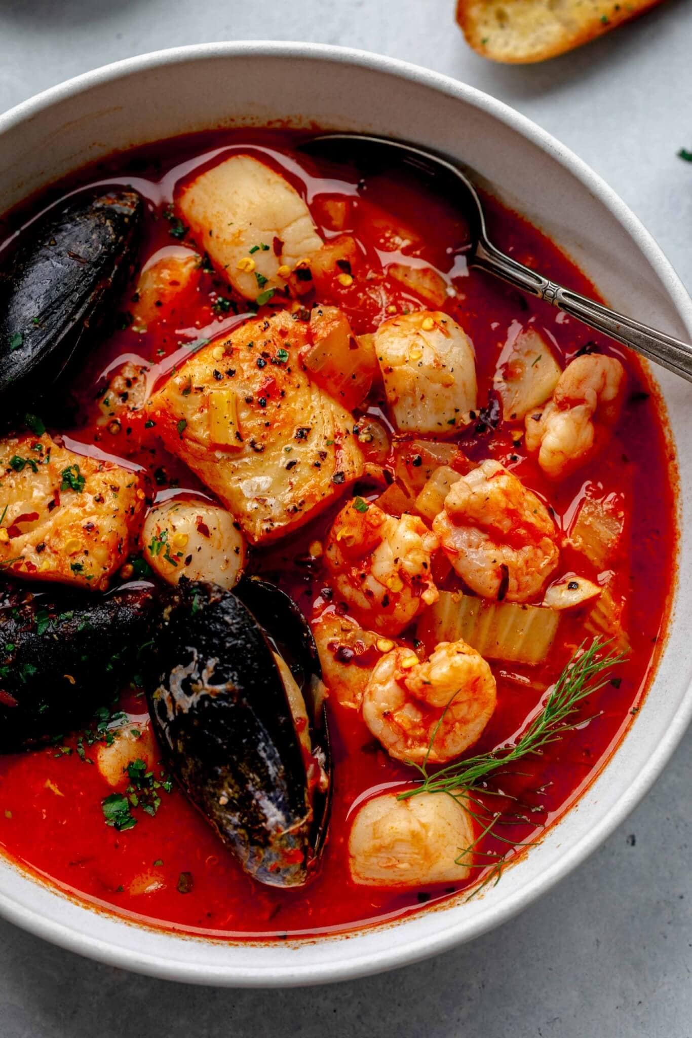 Overhead shot of cioppino in white bowl with spoon.