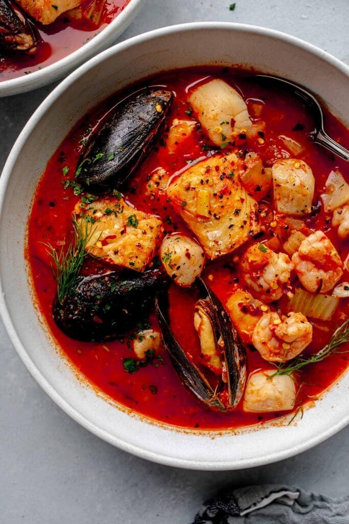 Overhead shot of cioppino in white bowl with spoon.