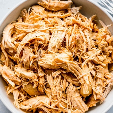 Shredded chicken in white bowl.