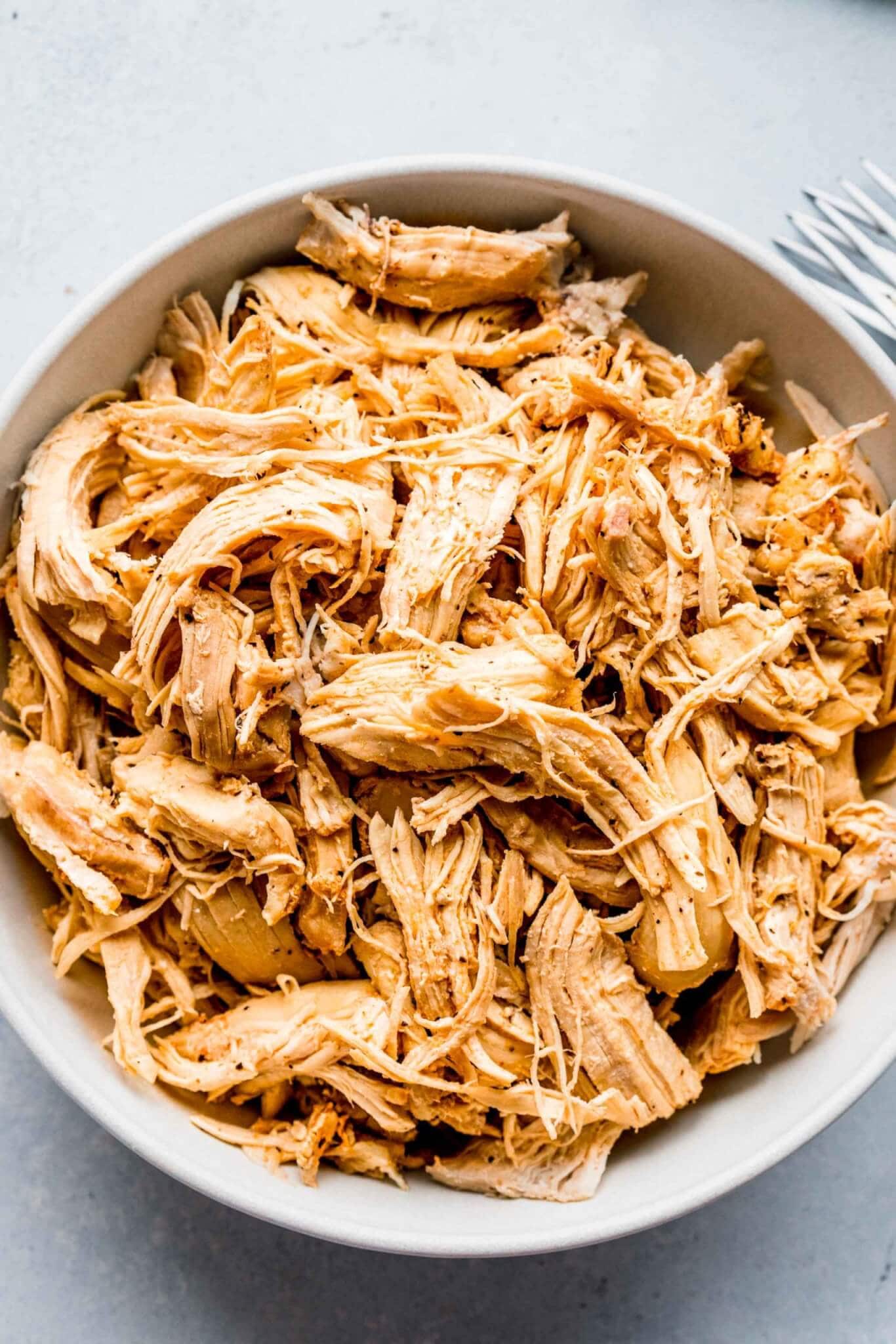 Shredded chicken in white bowl.