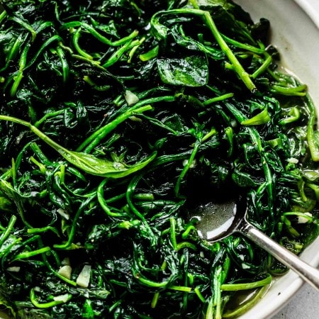 Sauteed spinach in white bowl.