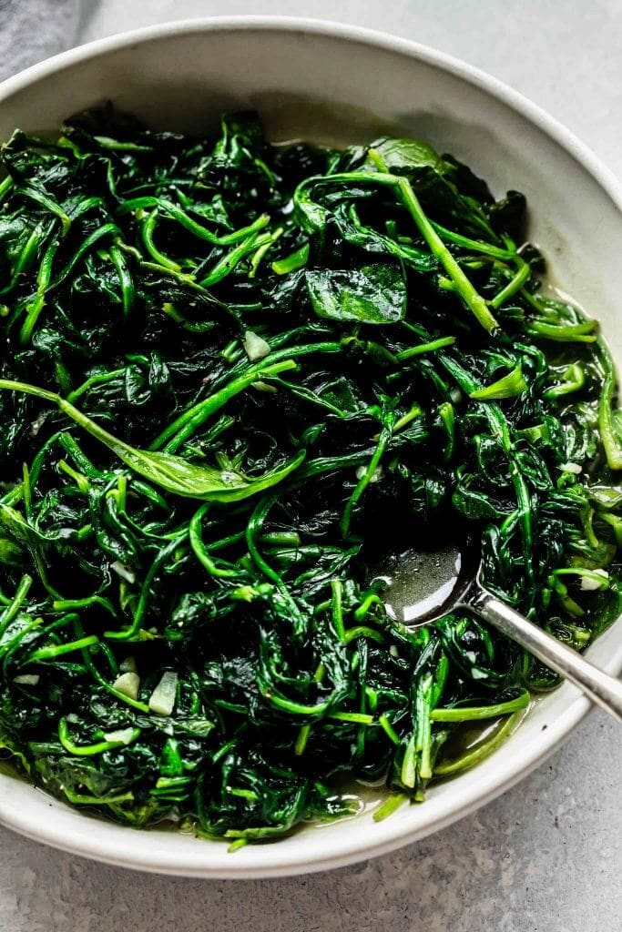 Sauteed spinach in white bowl.