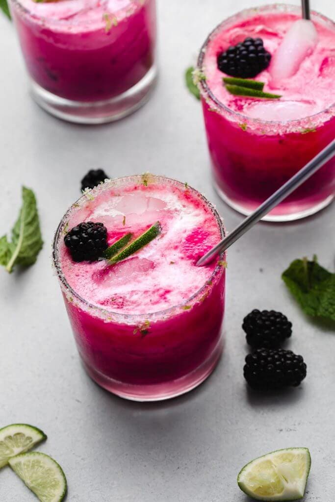 Three blackberry mojitos on counter. 