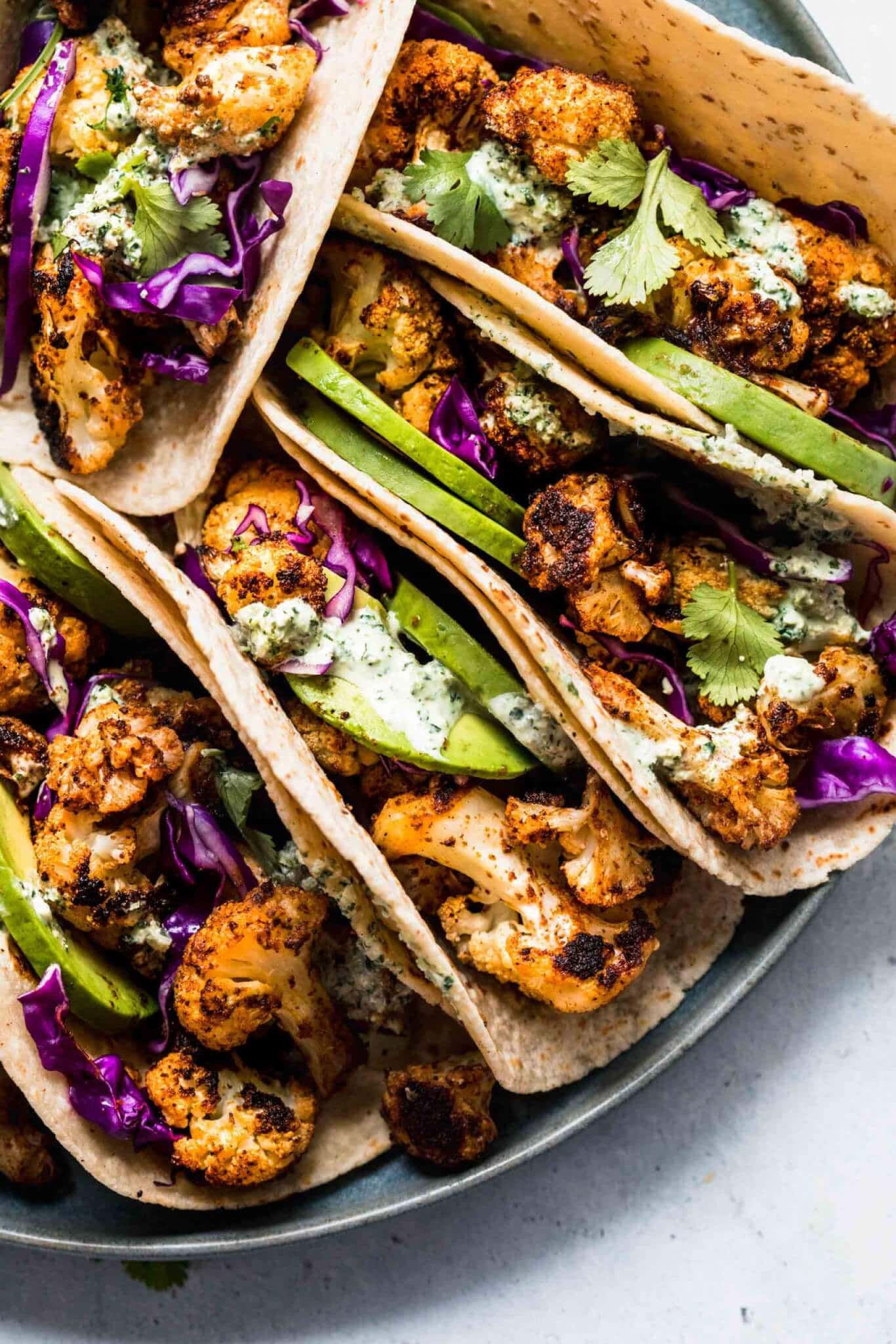 Overhead shot of tacos arranged on grey plate.