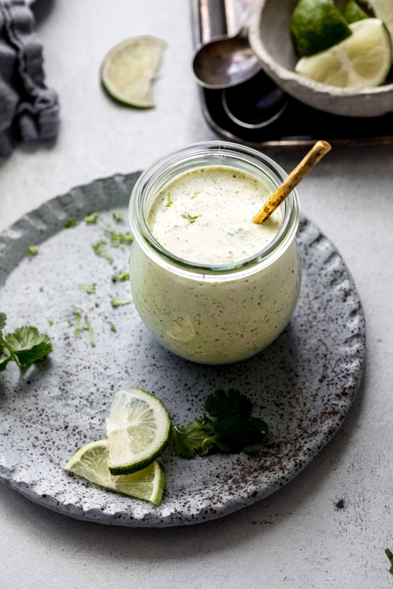 Side view of small container of cilantro lime crema with spoon.