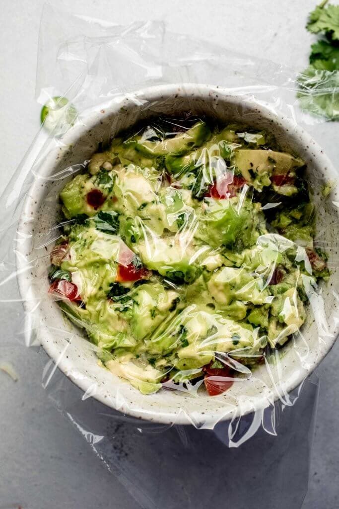 BOWL OF GUACAMOLE COVERED WITH SARAN WRAP. 