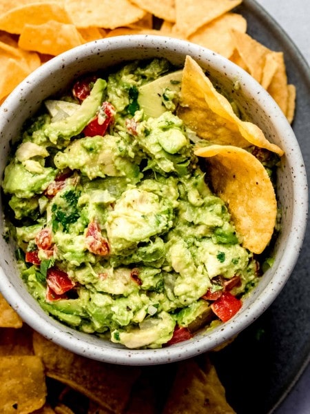 Bowl of guacamole on tray with chips.