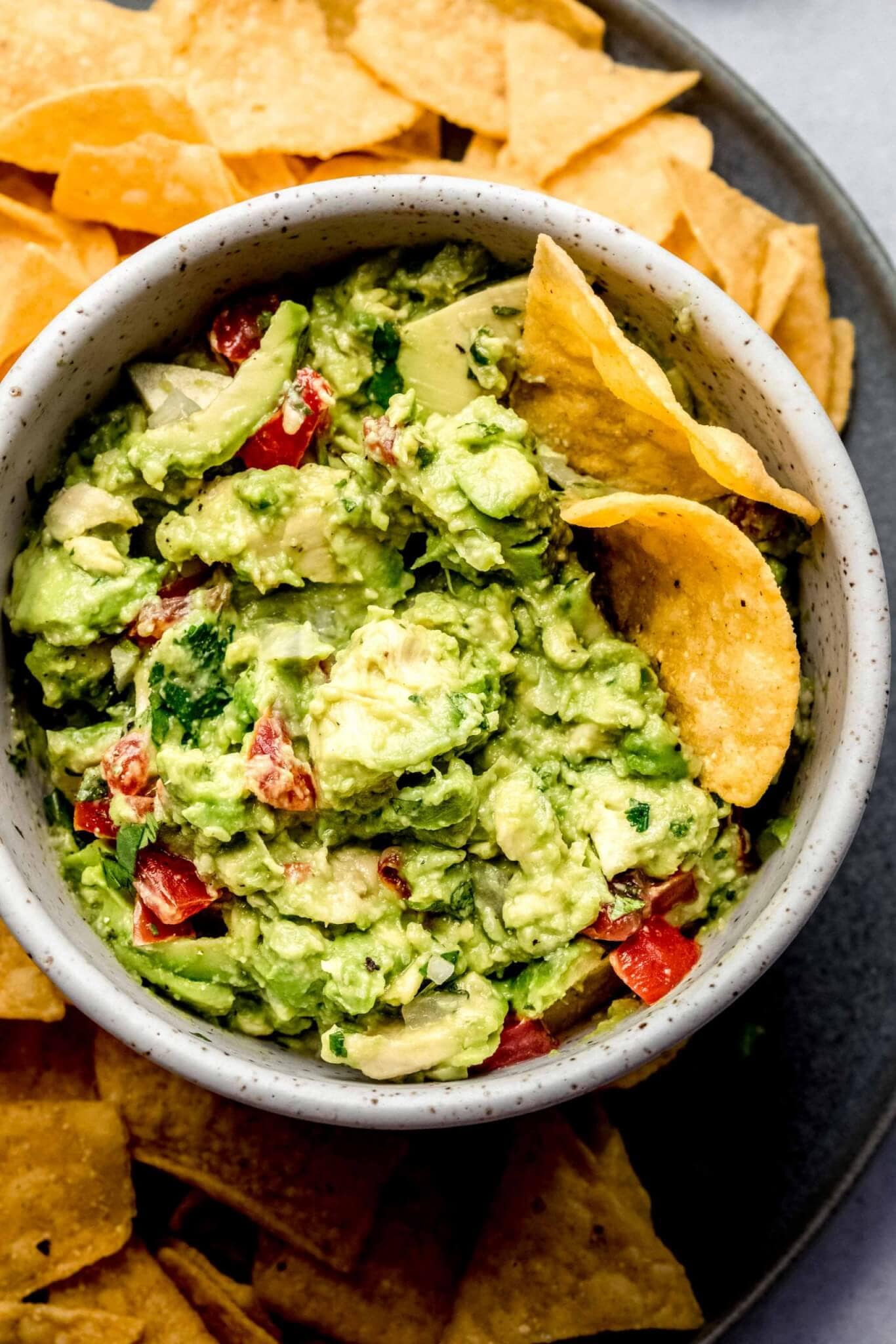 Bowl of guacamole on tray with chips.