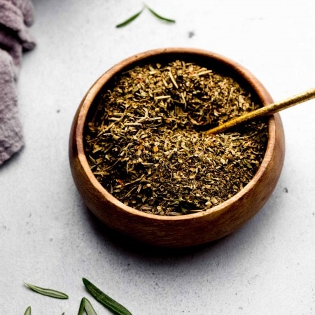 Side view of bowl of seasoning with small spoon.