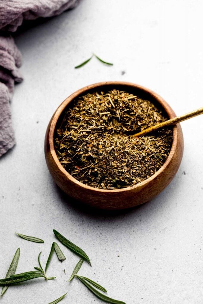 Side view of bowl of seasoning with small spoon.