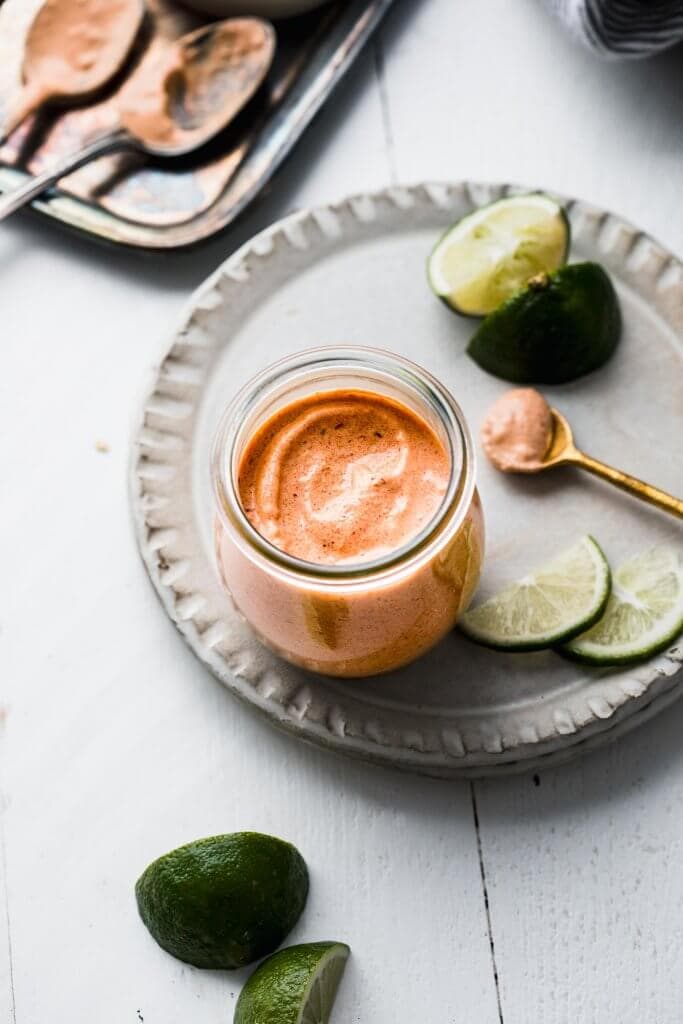 Quesadilla sauce in small jar next to serving spoon. 