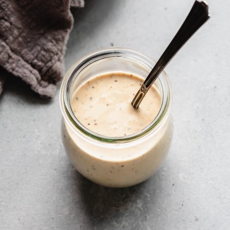 White bbq sauce in small jar with spoon.