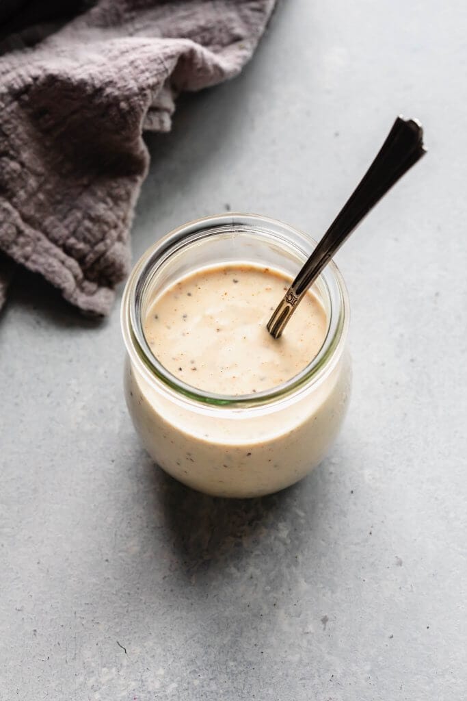 White bbq sauce in small jar with spoon.