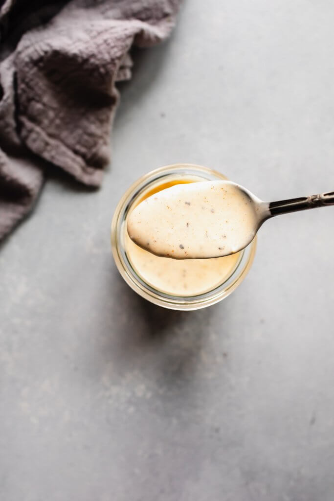 Spoon dipping into jar of bbq sauce. 