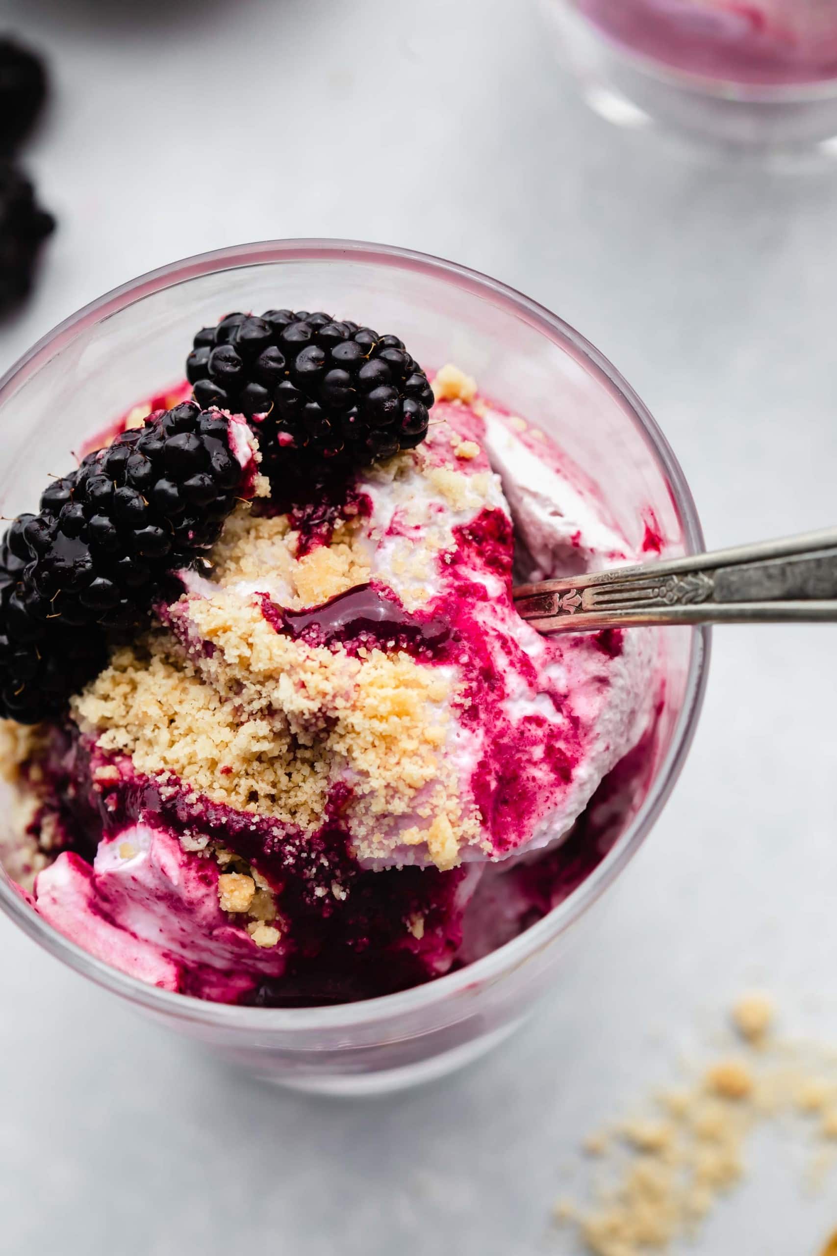 OVERHEAD SHOT OF BLACKBERRY FOOL IN SERVING GLASS WITH SPOON.