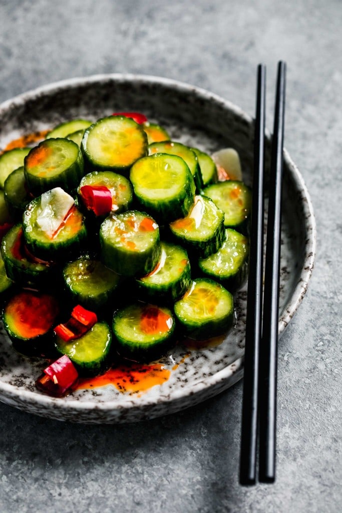 Side view of cucumber slices arranged on plate drizzled with chile oil. 