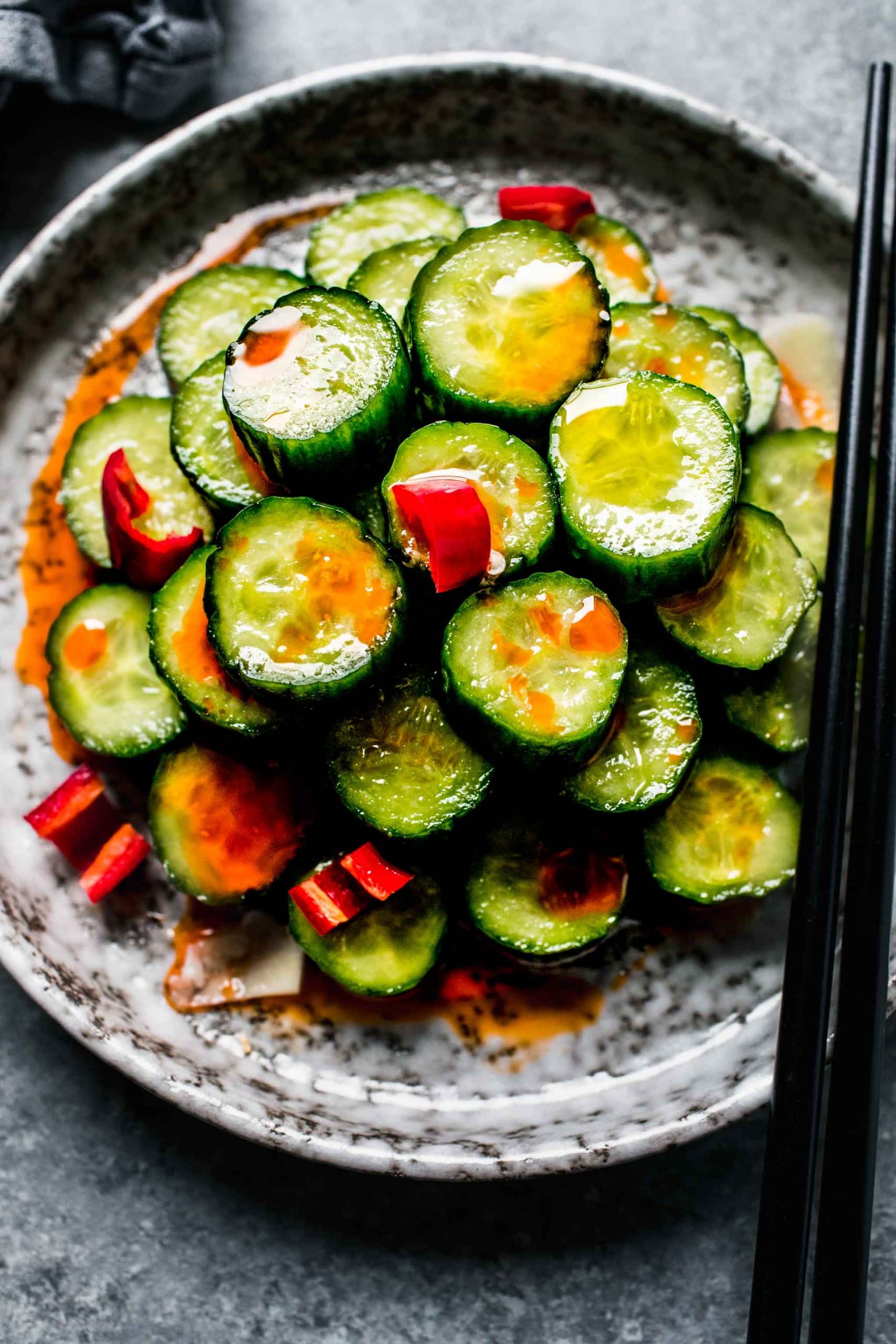 Overhead shot of din tai fung cucumber salad on grey plate with chopsticks.