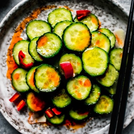 Overhead shot of din tai fung cucumber salad on grey plate with chopsticks.