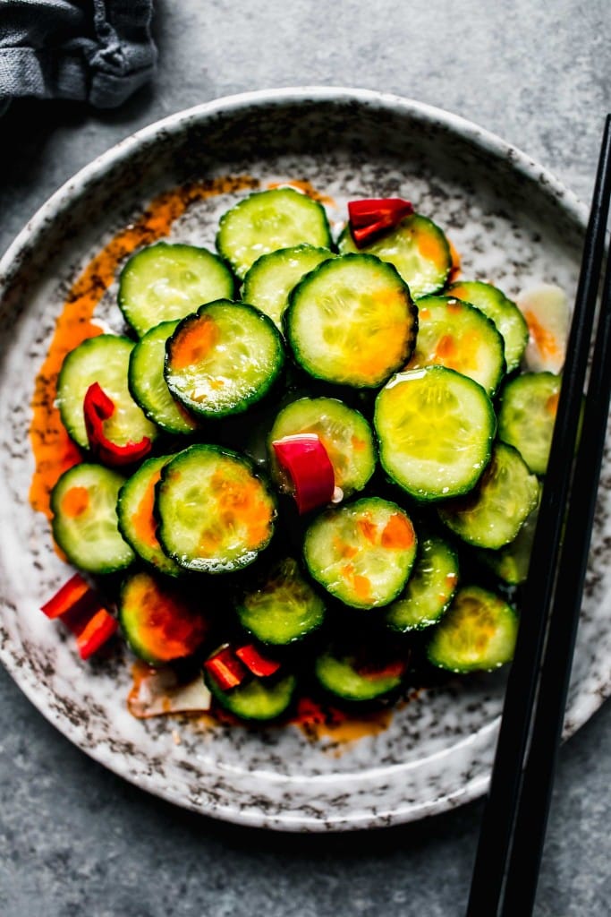 Overhead shot of din tai fung cucumber salad on grey plate with chopsticks.