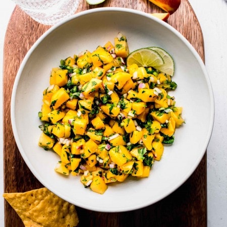 Bowl of mango salsa in serving bowl next to tortilla chips.