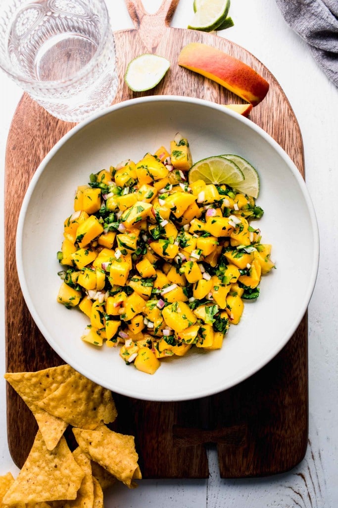 Bowl of mango salsa in serving bowl next to tortilla chips.