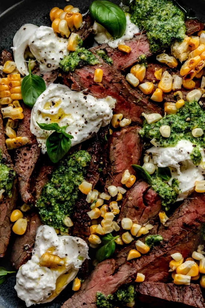 Overhead close up of grilled flank steak with burrata cheese. 