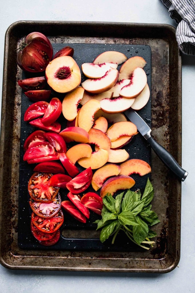 Sliced tomatoes and peaches on tray. 