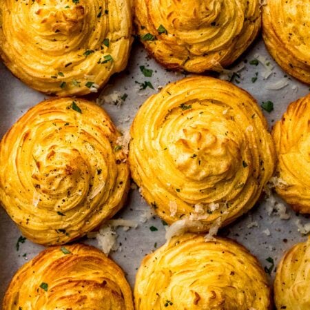 COOKED DUCHESS POTATOES ON BAKING SHEET NEXT TO SPATULA.