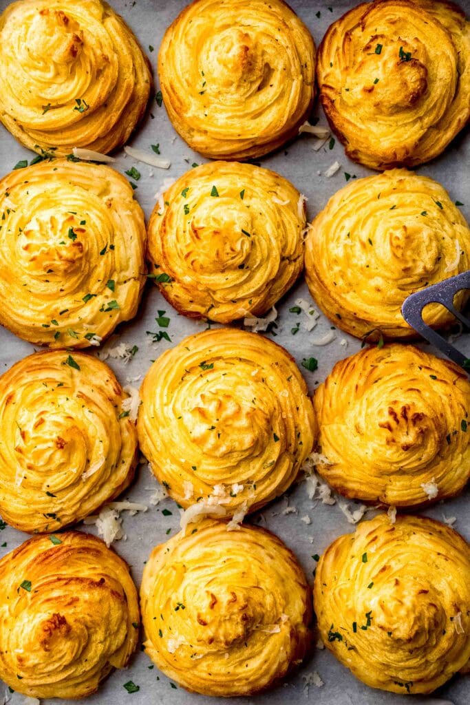 COOKED DUCHESS POTATOES ON TRAY SPRINKLED WITH PARSLEY. 