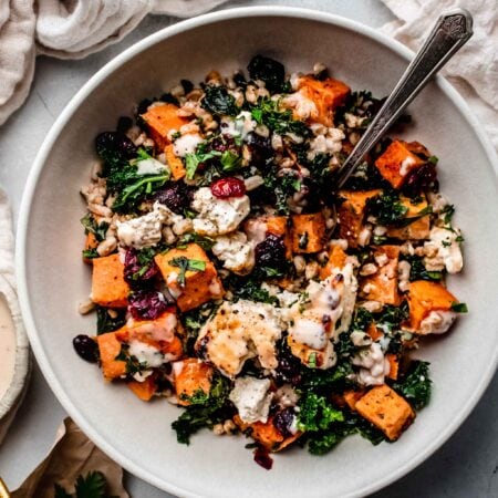 Roasted feta tossed with farro, sweet potatoes and kale in white bowl.
