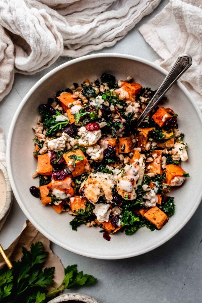 Roasted feta tossed with farro, sweet potatoes and kale in white bowl.