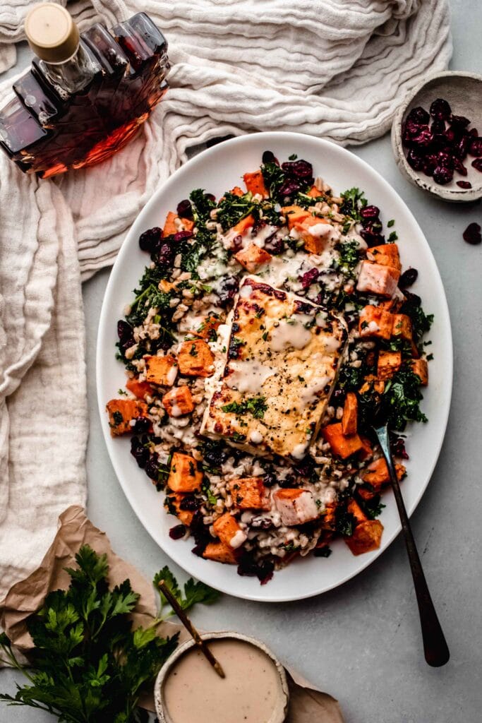 Block of roasted feta on bed of farro, sweet potatoes and kale. 