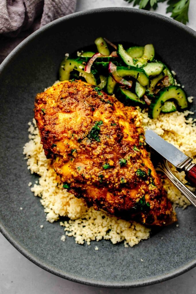 Curried chicken breast on bowl of couscous.