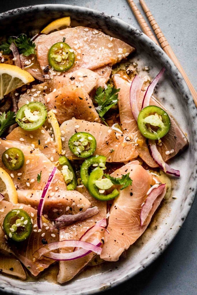 Plate of yellowtail crudo topped with serrano peppers. 