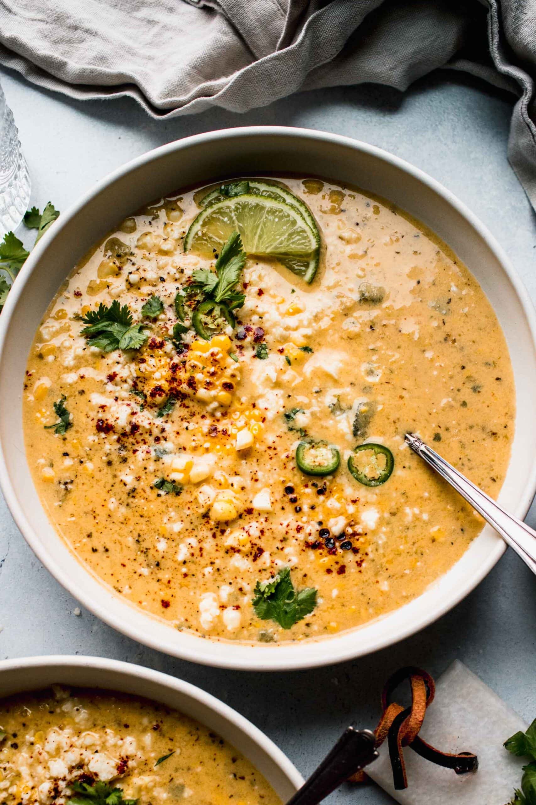 Bowl of Mexican Corn Soup garnished with cliantro, chile powder and lime wedges.