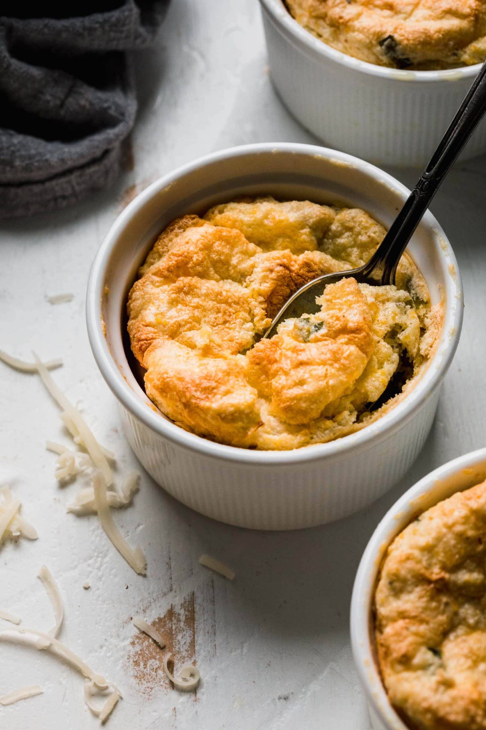 Side view of spoon bread in ramekin with spoon.