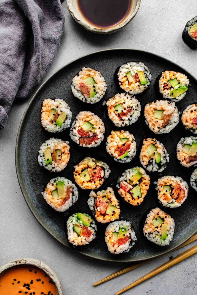 Vegetarian sushi rolls arranged on plate with bowl of spicy mayo.