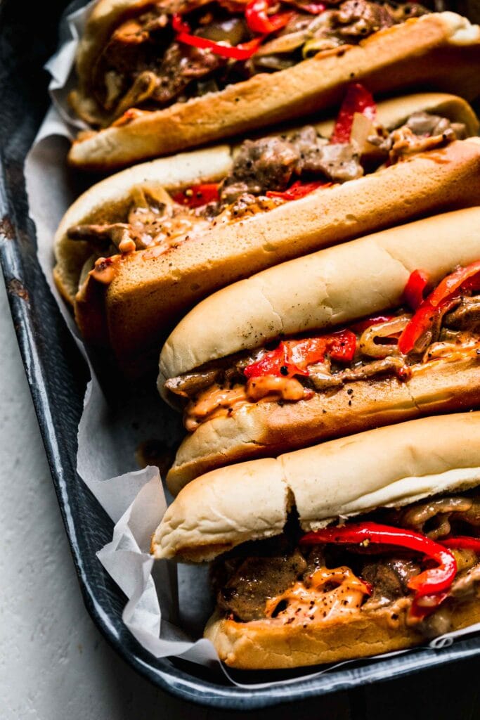 Close up of cheesesteak sandwiches in tray. 