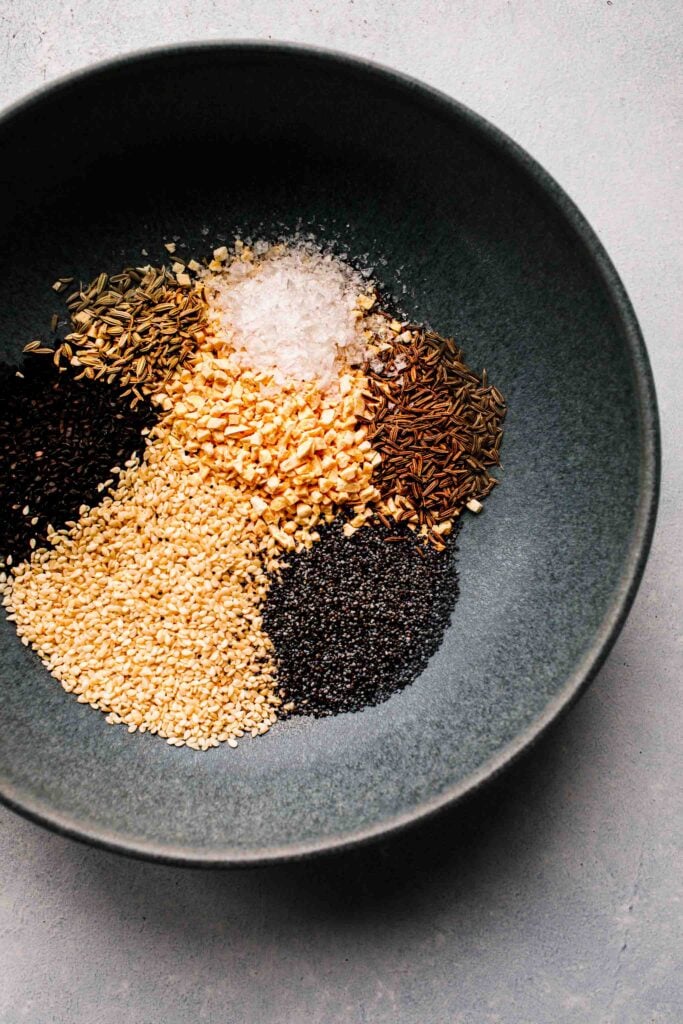 Spices poured into grey bowl before mixing.