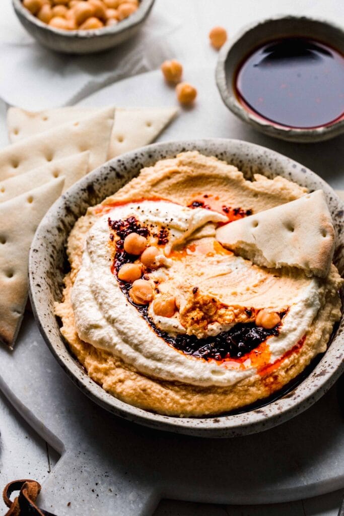 Side view of bowl of hummus topped with whipped feta. 