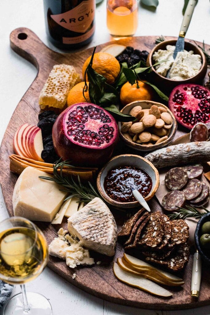 Cheese board arranged next to glasses of sparkling wine. 