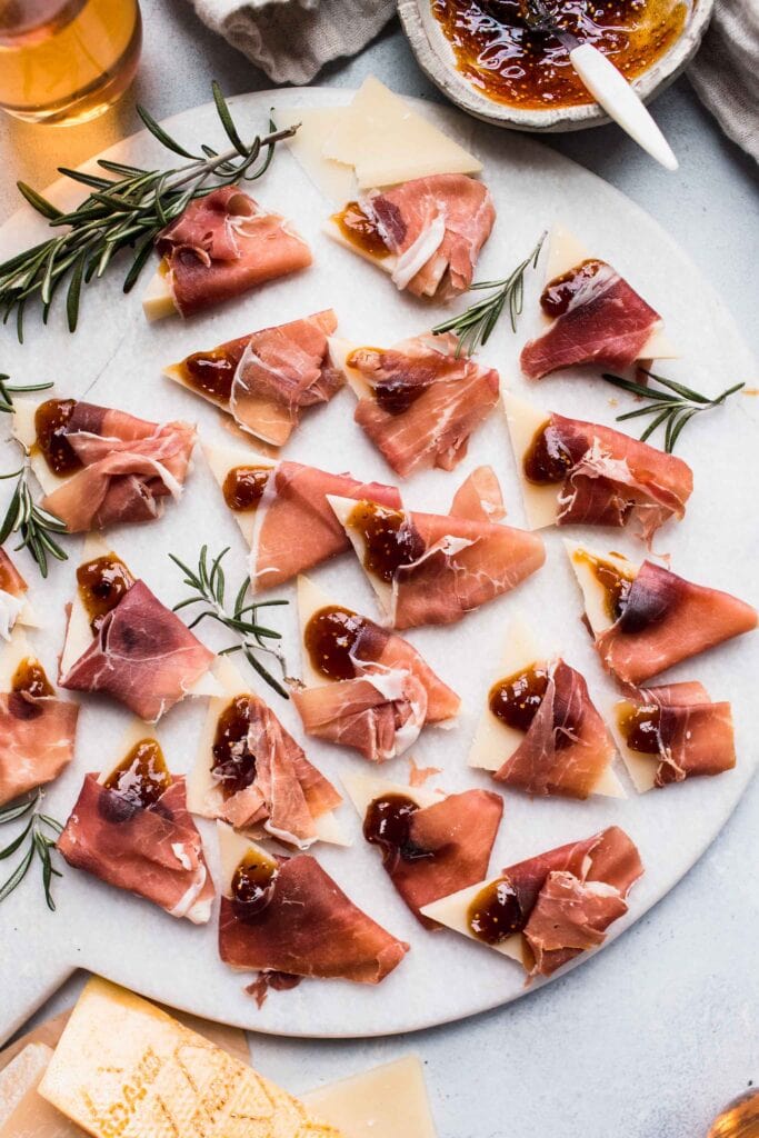 Prosciutto grana padano bites on white serving tray. 