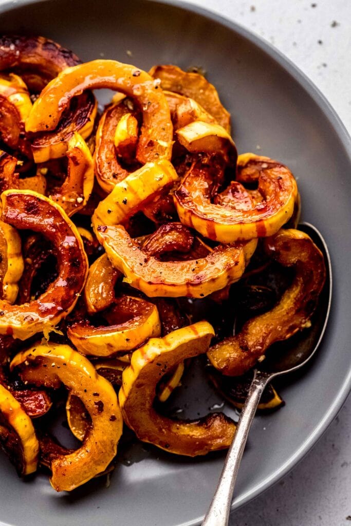 Delicata squash arranged in grey bowl with spoon. 