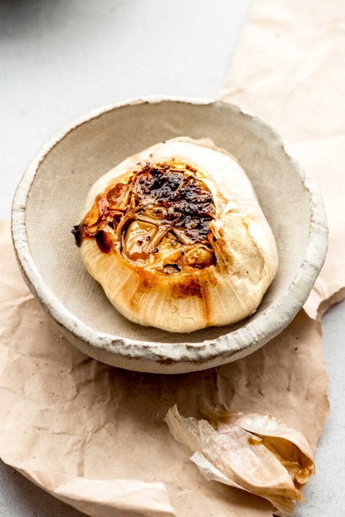 HEAD OF ROASTED GARLIC IN SMALL SERVING DISH. 