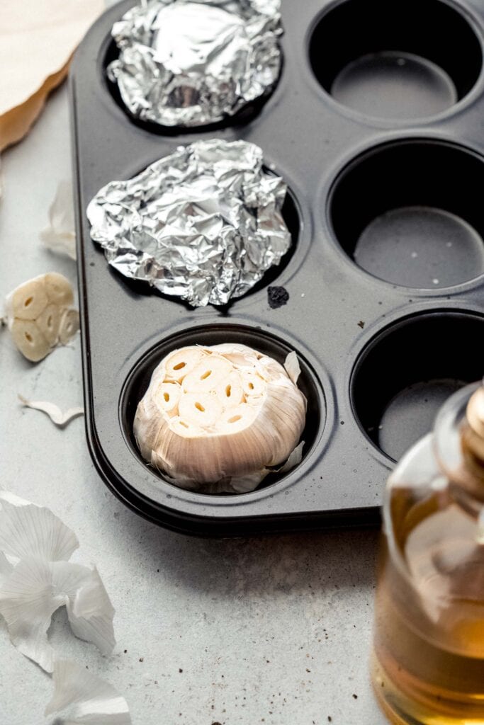 HEADS OF GARLIC IN MUFFIN TIN COVERED WITH FOIL. 