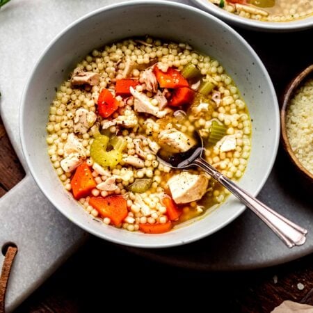 Two bowls of chicken carcass soup with spoon.