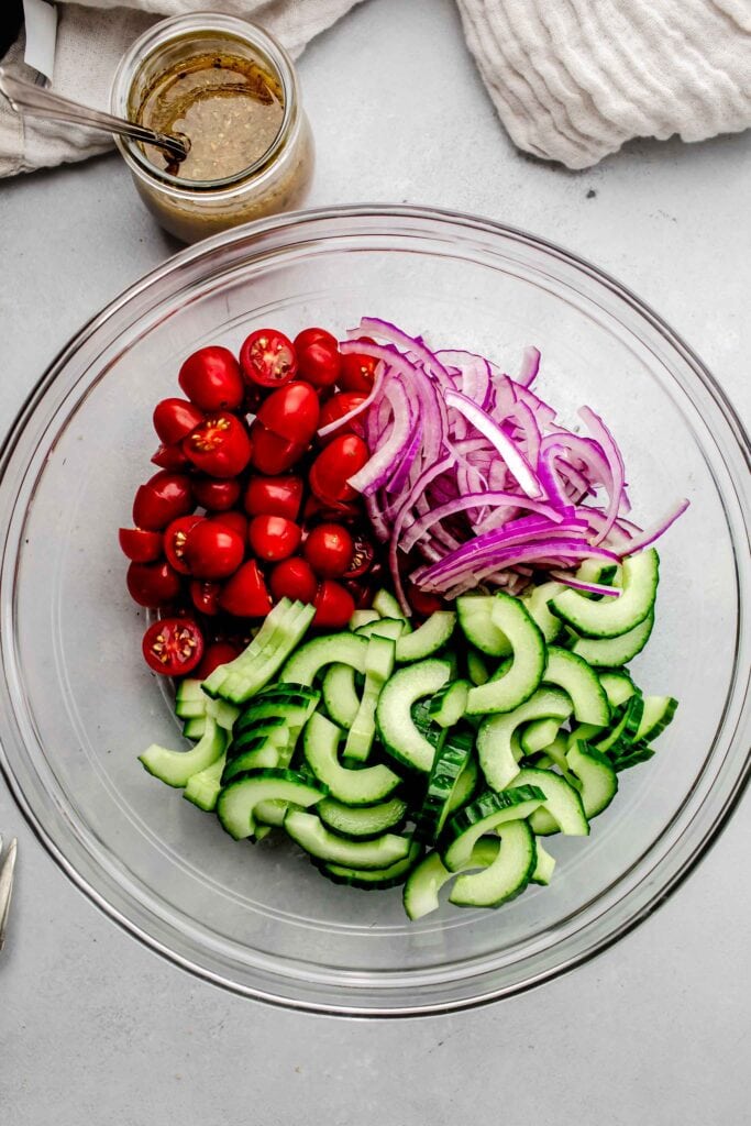 Chopped tomato, red onion and cucumber in mixing bowl before combining. 